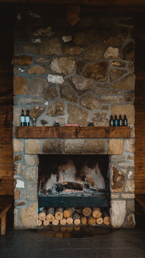 A large rustic stone fireplace with bottles ot the mantel