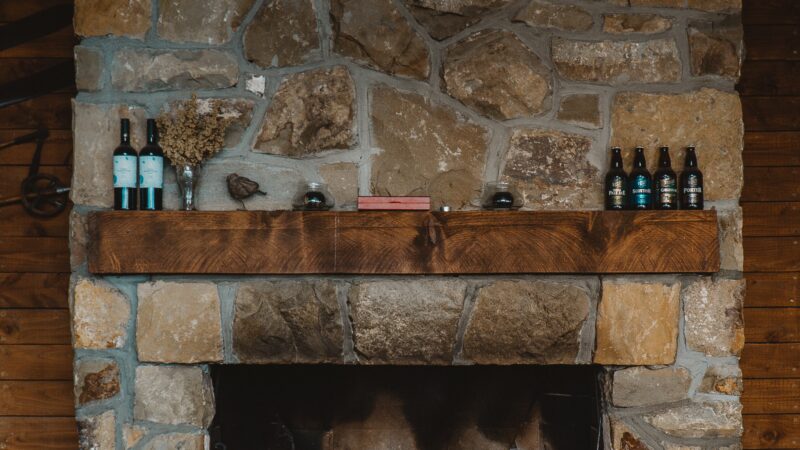A large rustic stone fireplace with bottles ot the mantel