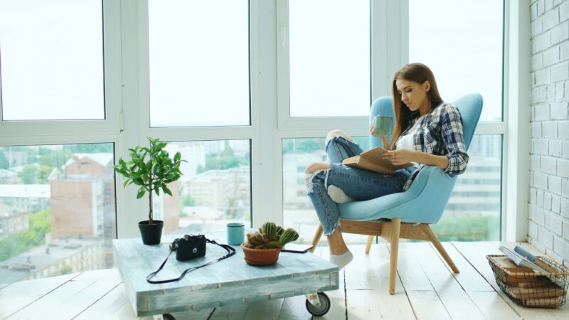 A woman is chilling in front of windows.